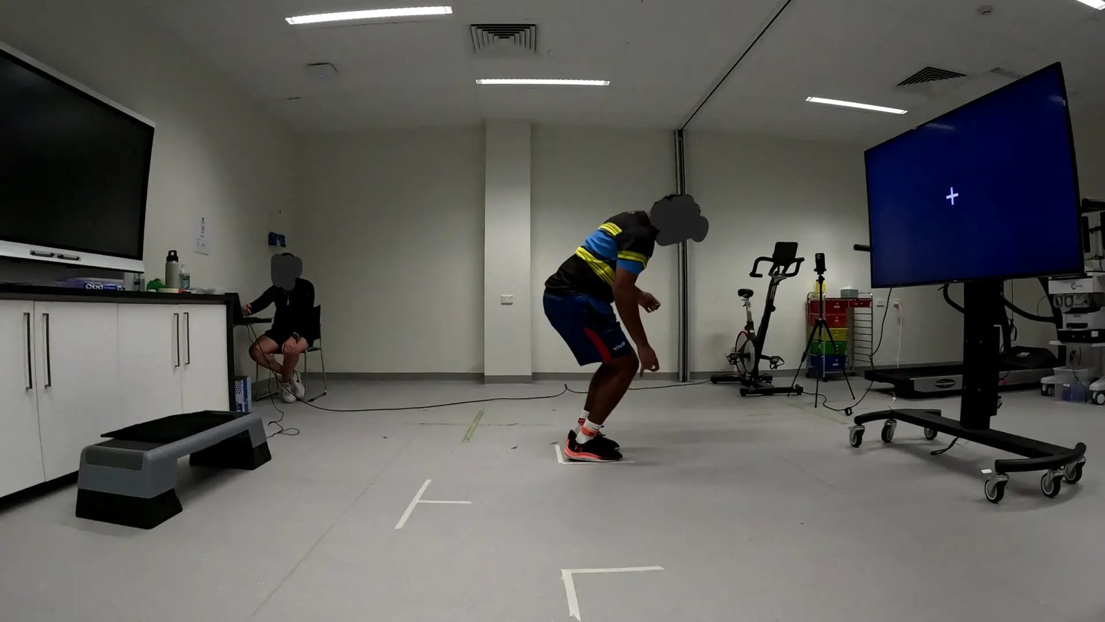 Athlete landing in the taped zone, knees bent, reading the cue on the display.